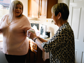 woman giving mug to another woman 