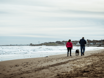 man and woman walking on beach