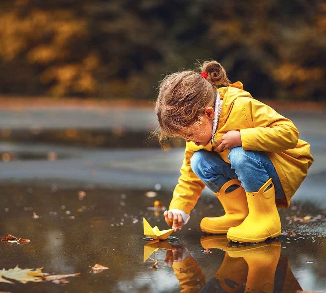 young girl in wellies standing in puddle